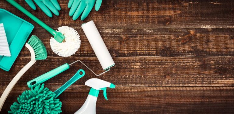 Teal cleaning products and tools on a dark wood floor.