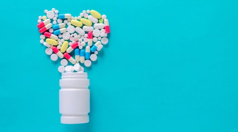 Multi-color pills spilling out of a white bottle on a blue background.